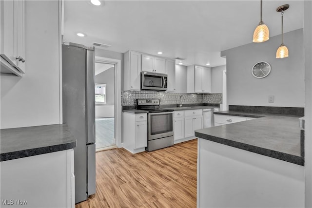 kitchen with appliances with stainless steel finishes, dark countertops, a sink, and white cabinets