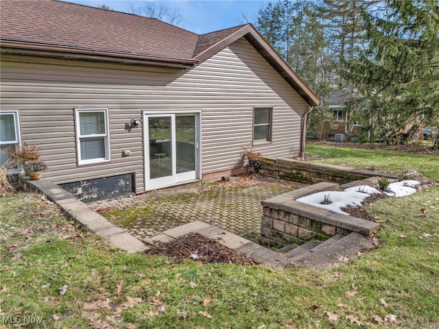 rear view of property featuring a shingled roof, a patio area, and a yard