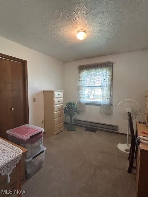 miscellaneous room with a baseboard heating unit, carpet floors, and a textured ceiling