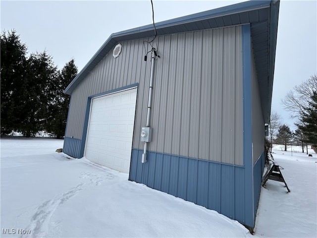 snow covered garage featuring a detached garage