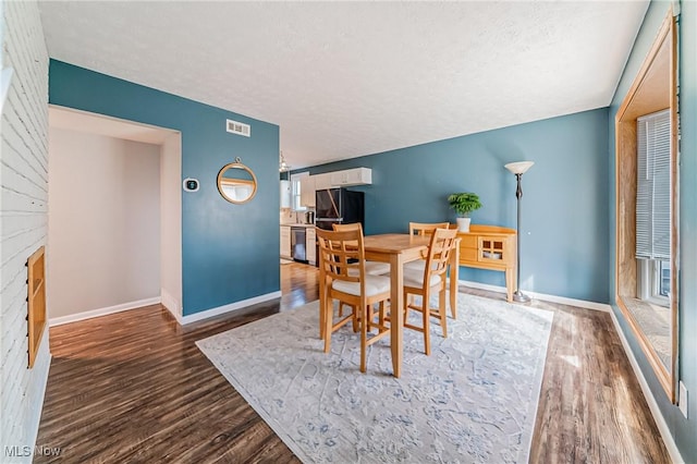 dining room featuring a textured ceiling, baseboards, and wood finished floors