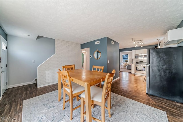 dining room featuring a textured ceiling, baseboards, and wood finished floors