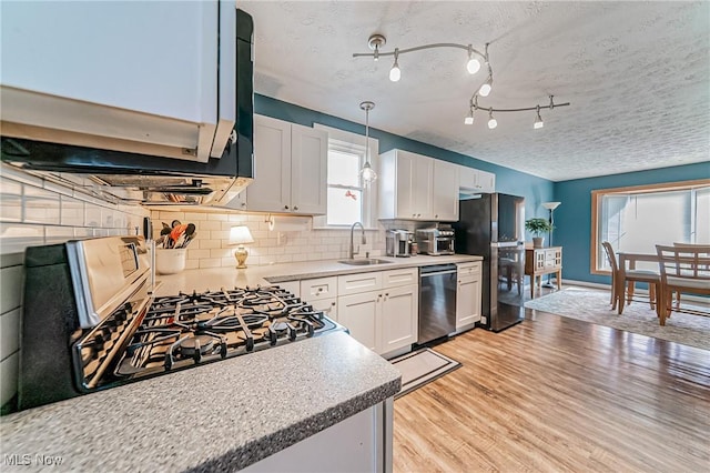 kitchen with a sink, white cabinetry, appliances with stainless steel finishes, backsplash, and light wood finished floors