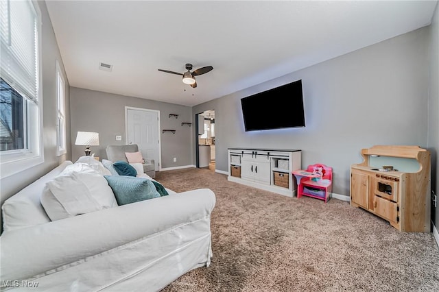 carpeted living area featuring a wealth of natural light, visible vents, and baseboards