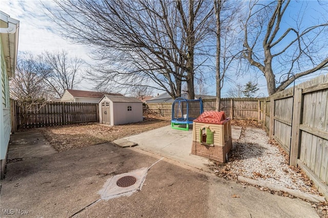 view of yard featuring an outbuilding, a patio, a fenced backyard, a storage shed, and a trampoline