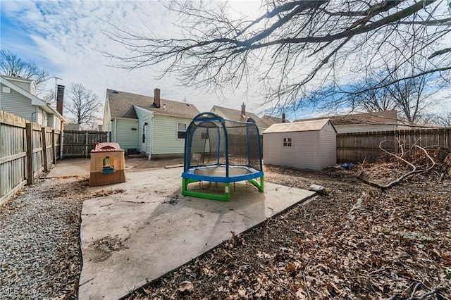 view of yard with an outbuilding, a patio, a fenced backyard, a shed, and a trampoline