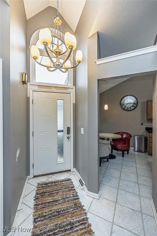 entrance foyer with high vaulted ceiling, a notable chandelier, and baseboards