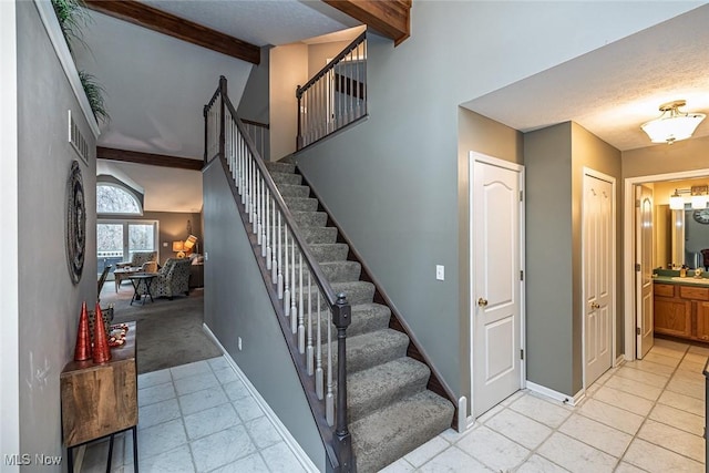 staircase with a towering ceiling, baseboards, and beamed ceiling