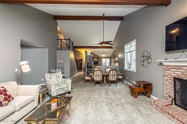 carpeted living area with ceiling fan, lofted ceiling with beams, a brick fireplace, and baseboards