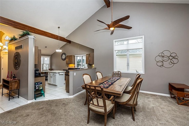 dining room featuring light carpet, beam ceiling, and a healthy amount of sunlight