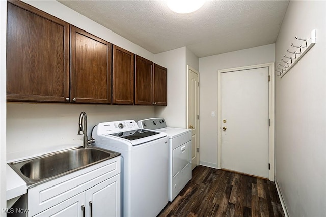 laundry area with cabinet space, washer and clothes dryer, dark wood-type flooring, a textured ceiling, and a sink