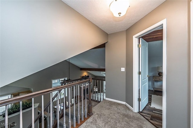 hallway featuring carpet flooring, a textured ceiling, and baseboards