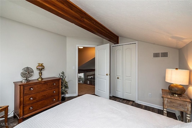 bedroom featuring dark wood finished floors, a closet, visible vents, lofted ceiling with beams, and a textured ceiling