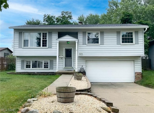 split foyer home with an attached garage, driveway, a front lawn, and fence