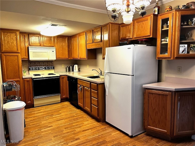 kitchen featuring white appliances, ornamental molding, brown cabinetry, and a sink