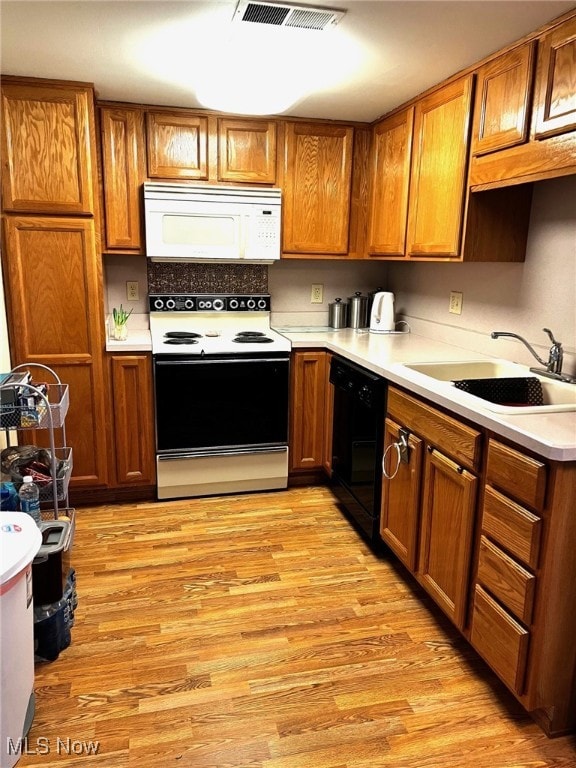 kitchen featuring white microwave, range with electric cooktop, visible vents, light wood-style floors, and dishwasher