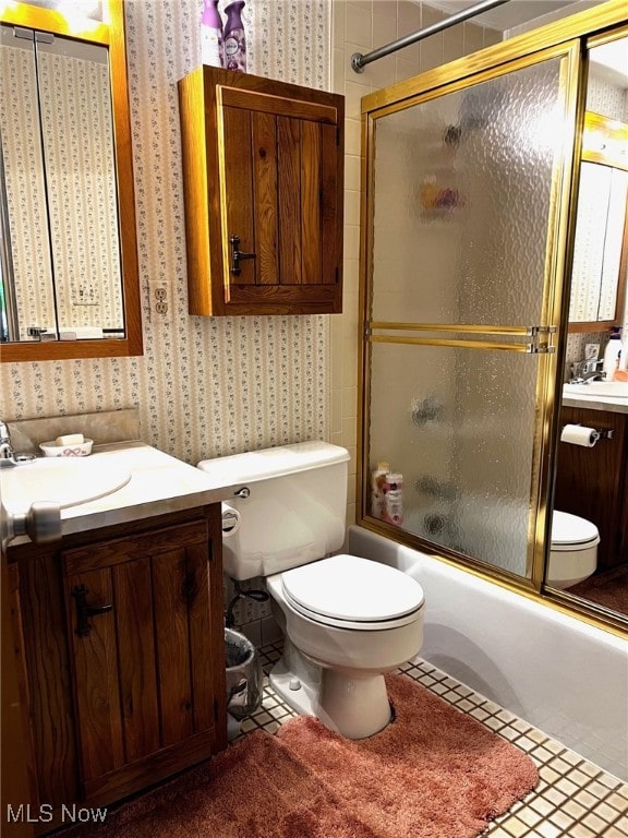 bathroom with enclosed tub / shower combo, toilet, vanity, and wallpapered walls