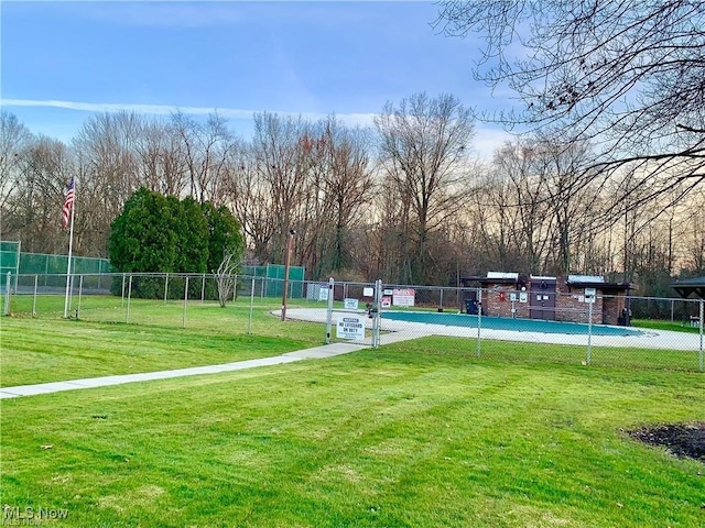 view of property's community featuring a lawn and fence