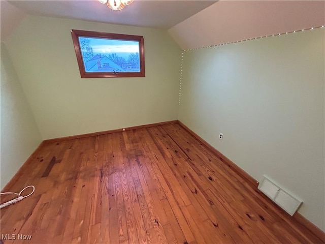 bonus room featuring hardwood / wood-style flooring, baseboards, visible vents, and vaulted ceiling