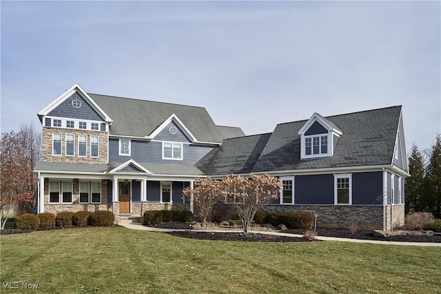 view of front of house featuring a front yard, stone siding, and covered porch