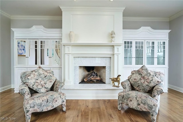 sitting room featuring crown molding, a premium fireplace, baseboards, and wood finished floors