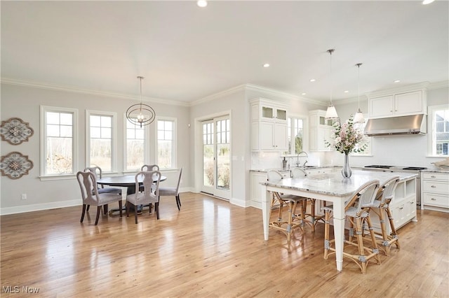 dining area with a healthy amount of sunlight, light wood-style flooring, ornamental molding, and baseboards