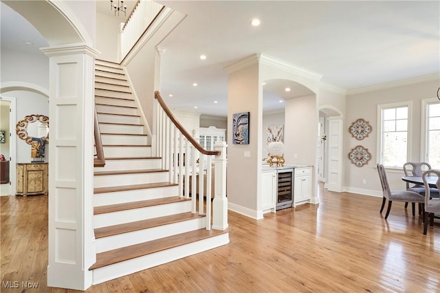 interior space with crown molding, wine cooler, baseboards, and wood finished floors