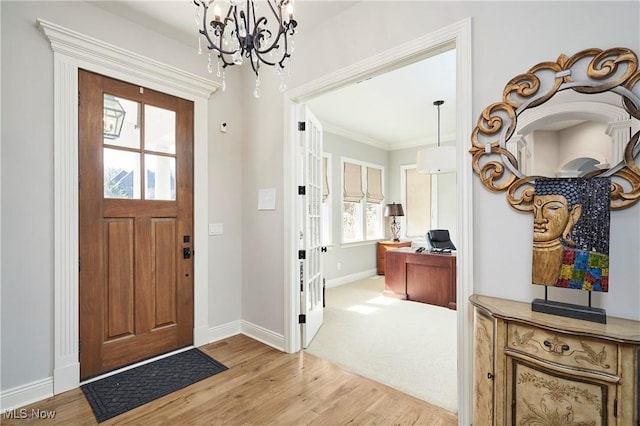 entryway with a notable chandelier, light wood finished floors, crown molding, and baseboards