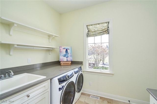 clothes washing area featuring visible vents, a sink, separate washer and dryer, laundry area, and baseboards