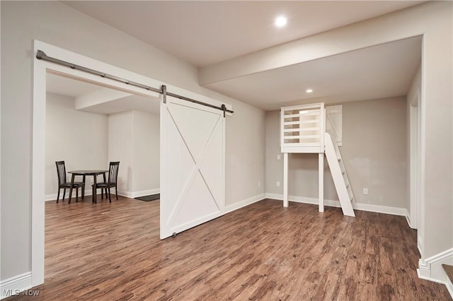 below grade area featuring a barn door, recessed lighting, wood finished floors, and baseboards