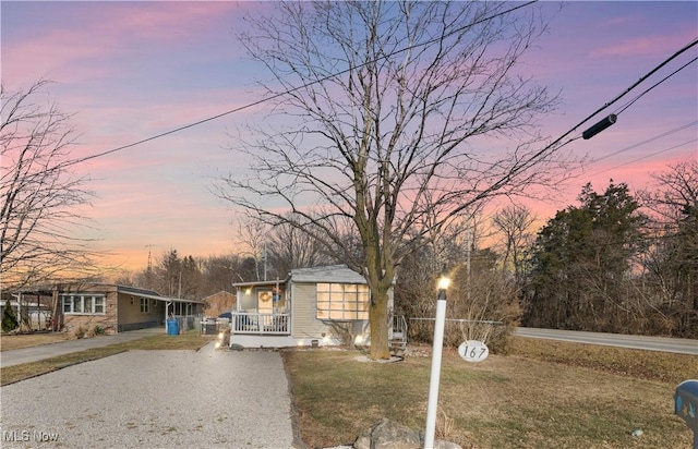 view of front of property featuring covered porch, driveway, and a yard