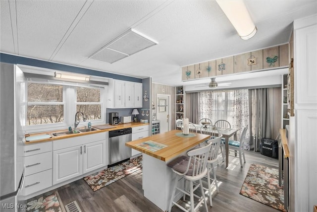 kitchen featuring dishwasher, a sink, wood counters, and white cabinets