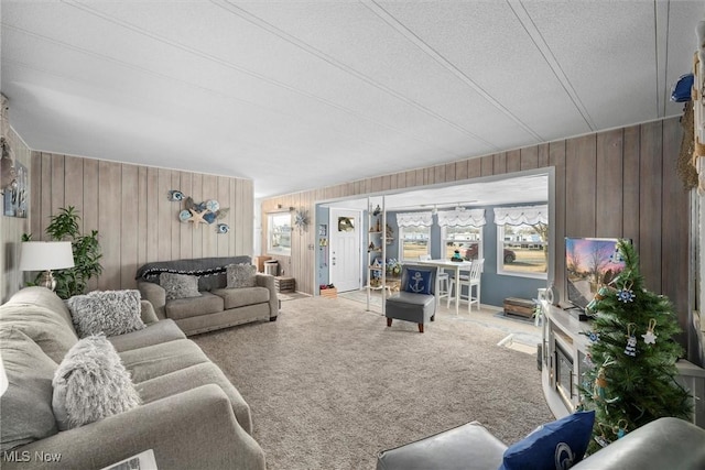 carpeted living area featuring a textured ceiling and wooden walls