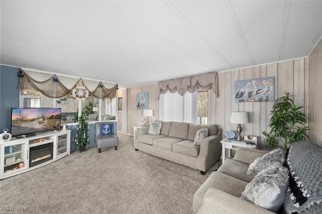 living area with wood walls, carpet flooring, and a glass covered fireplace