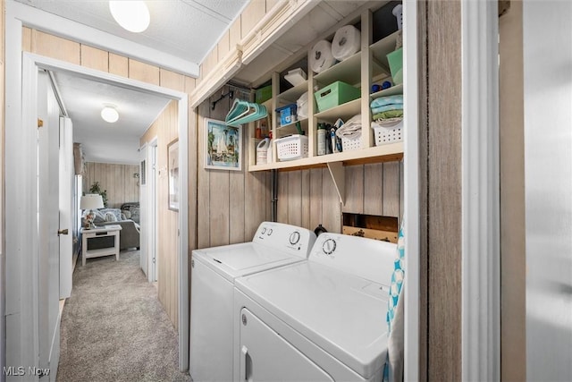 laundry area featuring laundry area, wood walls, washing machine and dryer, and light colored carpet