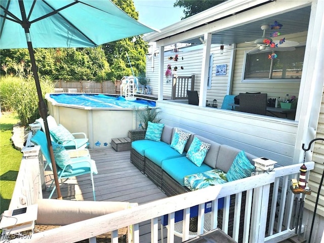 wooden deck with ceiling fan, outdoor lounge area, fence, and a fenced in pool