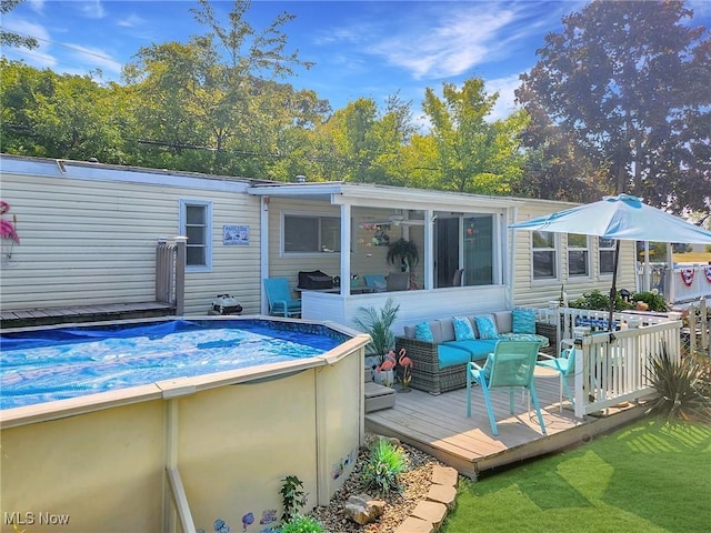 rear view of property featuring a sunroom, a deck, and an outdoor living space