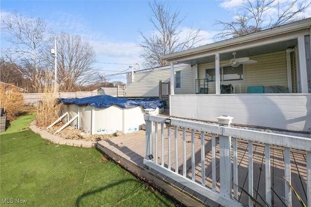 view of yard with a fenced in pool, fence, a deck, and a ceiling fan