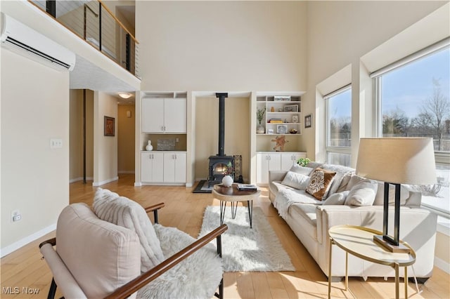 living room featuring a towering ceiling, light wood finished floors, and a wall mounted AC