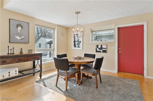 dining room with a chandelier, baseboards, a textured ceiling, and light wood finished floors