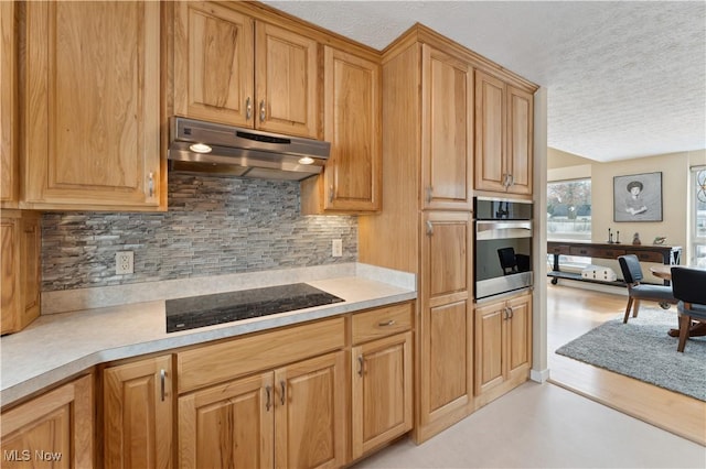 kitchen featuring light countertops, black electric cooktop, stainless steel oven, and under cabinet range hood