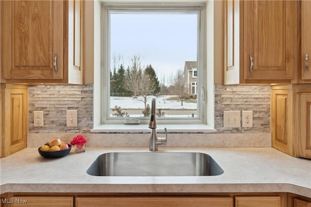 kitchen featuring decorative backsplash, light countertops, and a sink