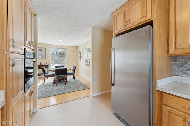 kitchen with baseboards, decorative backsplash, stainless steel appliances, a textured ceiling, and light countertops