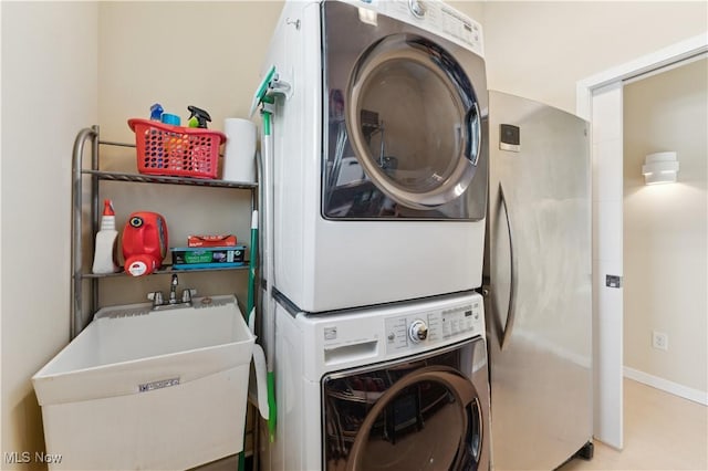 laundry room featuring stacked washer / dryer, laundry area, a sink, and baseboards