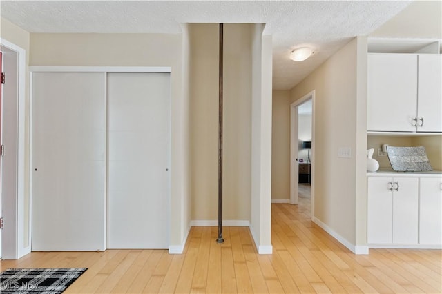 interior space with light wood finished floors, baseboards, and a textured ceiling