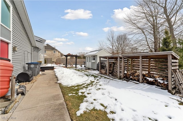 yard covered in snow featuring a shed, an outdoor structure, and fence