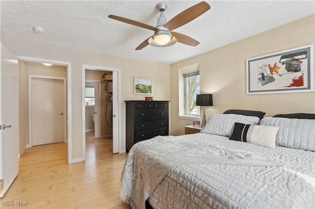 bedroom with baseboards, ceiling fan, a textured ceiling, and light wood finished floors