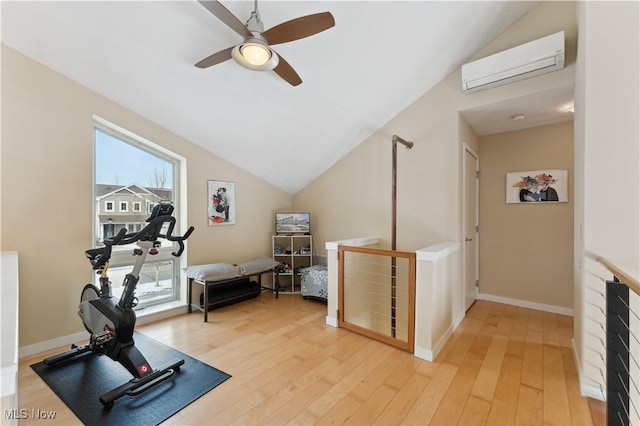 exercise room featuring lofted ceiling, light wood-type flooring, a wall mounted air conditioner, and baseboards