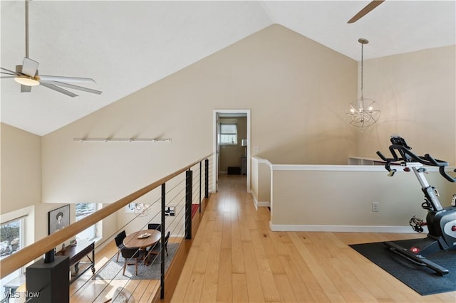 hallway with light wood finished floors, a chandelier, an upstairs landing, high vaulted ceiling, and baseboards