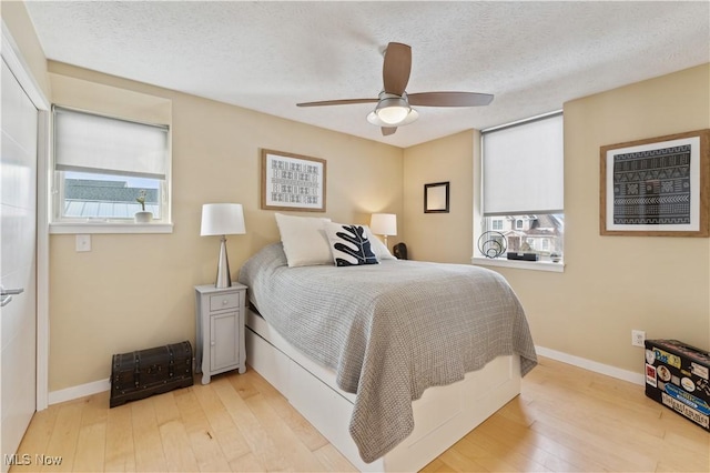 bedroom featuring light wood-style flooring, multiple windows, and a textured ceiling